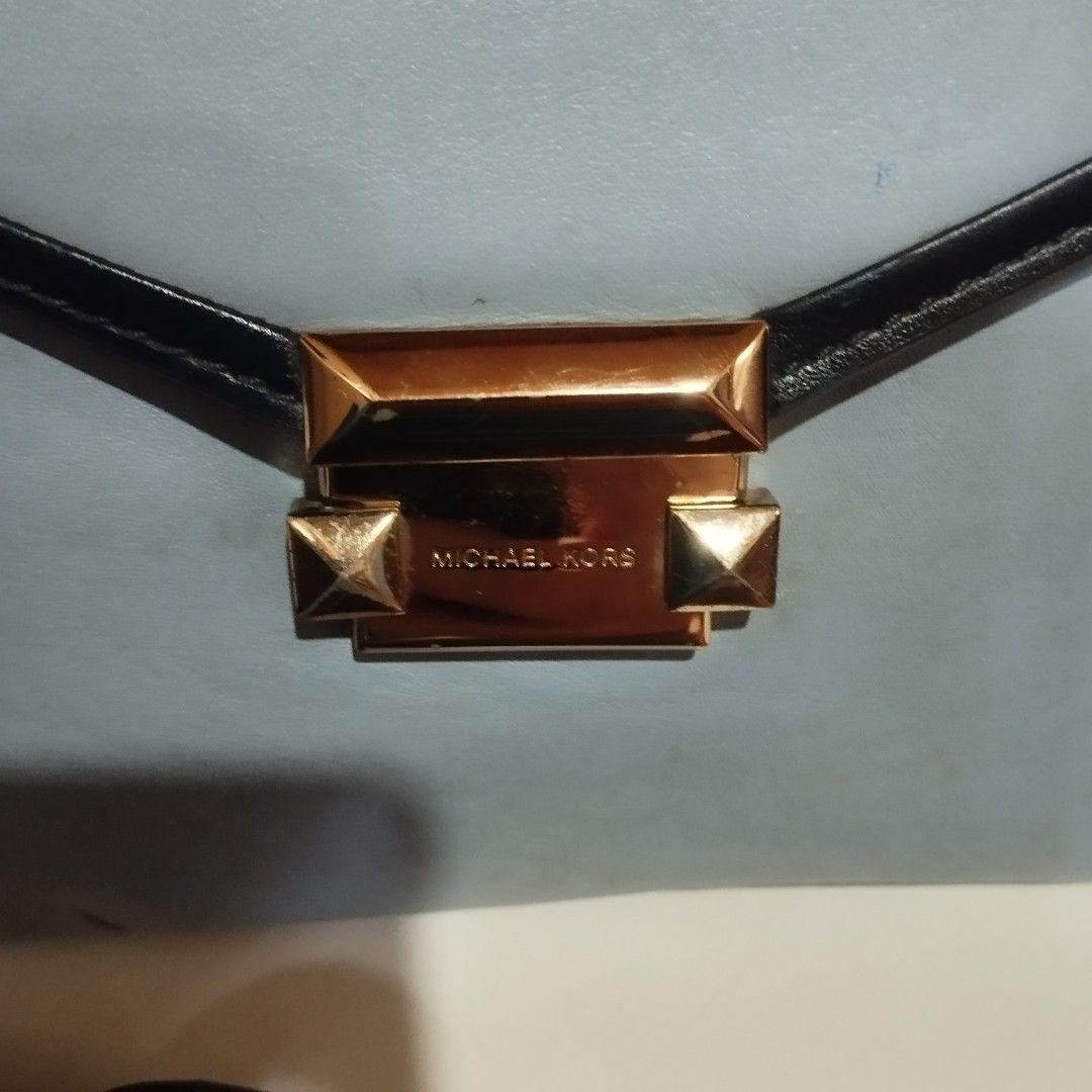 Michael Kors Blue and Black Leather Handbag (Category: Cross-body Bags) located in Manila. Submitted by lene48 (Listing ID 1468580205, Image 3). Description: - Brand: Michael Kors - Color: Light blue with black trim - Hardware: Gold-tone - Closure: Front flap with engraved logo lock clasp - Includes: Top handle and strap attachments (strap not included unless specified) - Condition: Pre-loved with minor scuffs, dark marks on the leather surface, 