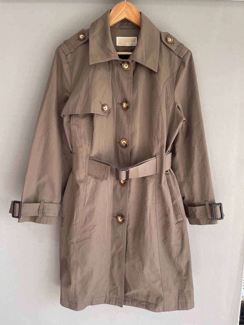 Michael Kors Brown Trench Coat (Category: Coats, Jackets and Outerwear) located in Mataasnakahoy. Submitted by zero4thrift (Listing ID 1468559482, Image 1). Description: - Brand: Michael Kors - Color: Brown - Style: Mid-length trench coat, great for cooler weather - Closure: Front tortoise-shell buttons - Details: Classic collar, shoulder epaulets, and cuff straps - Belt: Matching waist belt with a dark buckle included Actual size - 21” width - 3