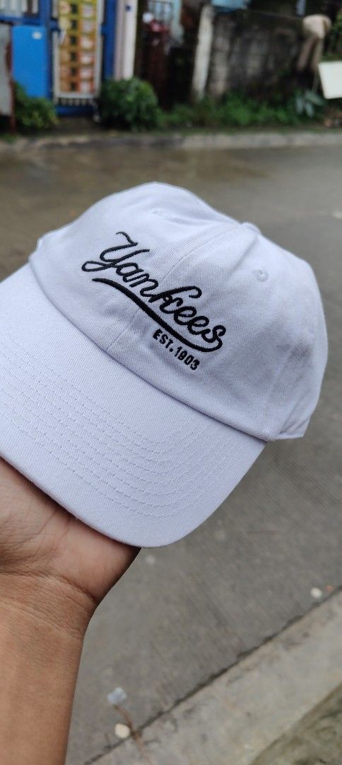 MLB New York Yankees White Baseball Cap (Category: Caps & Hats) located in Bulacan. Submitted by adrian2325 (Listing ID 1468602806, Image 2). Description: - Brand: MLB New York Yankees - Color: Clean white cotton - Design: Cursive 'EST. 1903' embroidery on the front - Fit: Adjustable strap at the back with premium metal buckle hardware - Condition: Brand new with inside tag and paper inserts still attached.