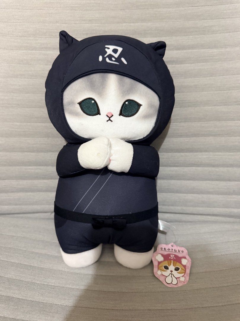 Mofusand Ninja Cat Stuffed Toy (Category: Plushies & Soft Toys) located in Pasig City. Submitted by thetravellingguyinstyle (Listing ID 1468689636, Image 1). Description: - Authentic Mofusand stuffed toy - Dressed in a cool black ninja outfit with Japanese kanji on the forehead hood - Features a cute grey tail at the back and tucked white paws in front - Made with ultra-soft, huggable material - Brand new with tag - From Tokyo Japan.