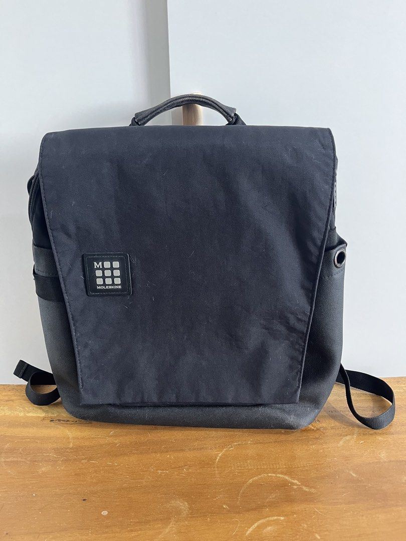 Moleskine Black Backpack (Category: Backpacks) located in Mandaluyong City. Submitted by unomarcelo001 (Listing ID 1468539756, Image 2). Description: laptop bag price still negotiable - Brand: Moleskine - Color: Classic Black - Material: Durable canvas-like fabric - Design: Front flap closure with Moleskine logo patch, side metal grommet detail - Comfort: Top handle and adjustable shoulder straps - Usage: Ideal for daily commute, school, or trave