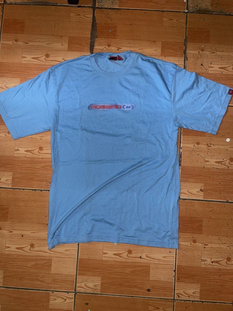 Mossimo 86 Vintage Light Blue T-Shirt (Category: Tshirts & Polo Shirts ) located in Manila. Submitted by joshua_guimeroy. (Listing ID 1468524537, Image 1). Description: - Brand: Mossimo 86 - Color: Light blue - Design: Logo graphic across the chest and matching larger print near the back collar - Details: Short sleeves with a small red brand tag on the left sleeve, standard crew neck fit - Flaw: Small stain visible on the lower back area - Condit