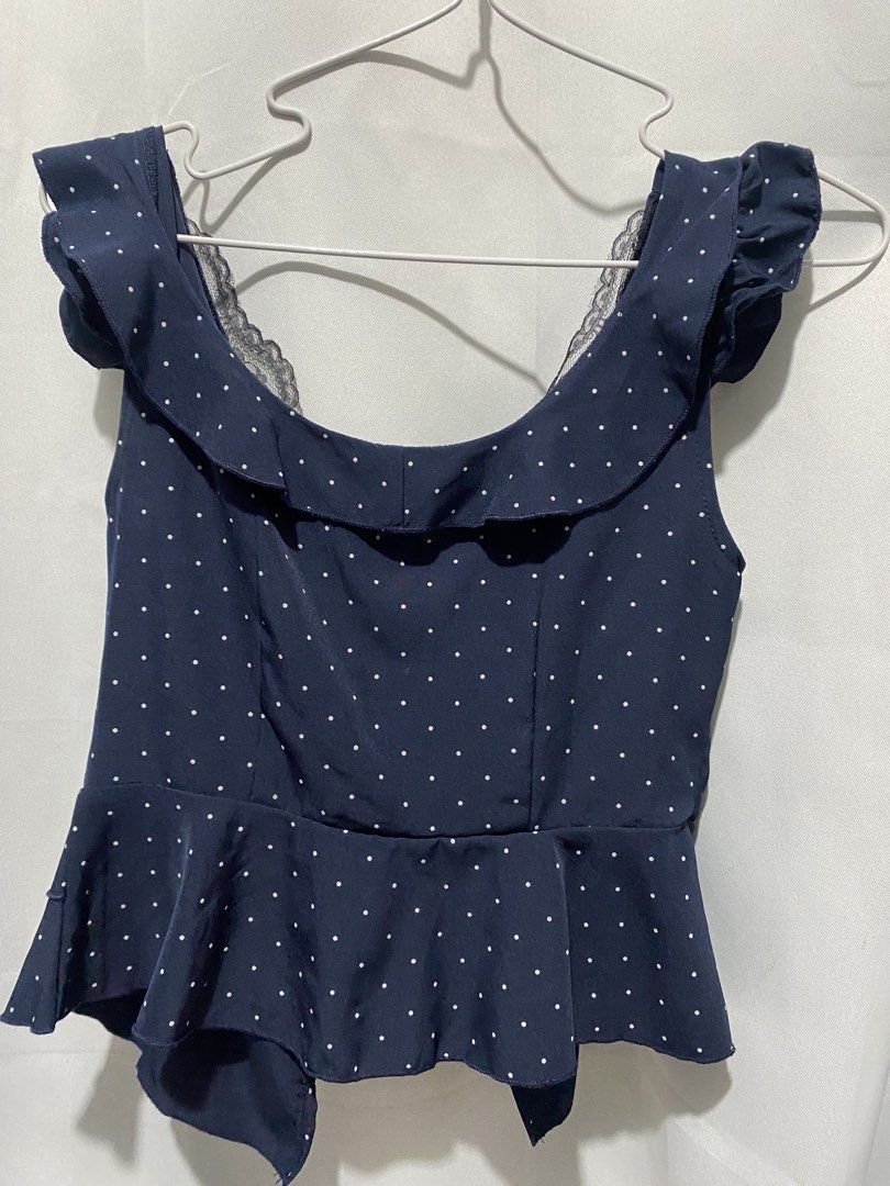 Navy Blue Polka Dot Ruffle Peplum Top (Category: Blouses) located in Binangonan. Submitted by lovegenn (Listing ID 1468545820, Image 2). Description: - Color: Navy blue with white polka dots - Design: Scoop neckline with black lace trim, button-down front with 5 black buttons - Sleeves: Ruffled cap sleeves - Cut: Peplum waist flare with layered hemline - Fabric: Lightweight and comfortable - Styling tip: Looks great with high-waisted jeans or ski