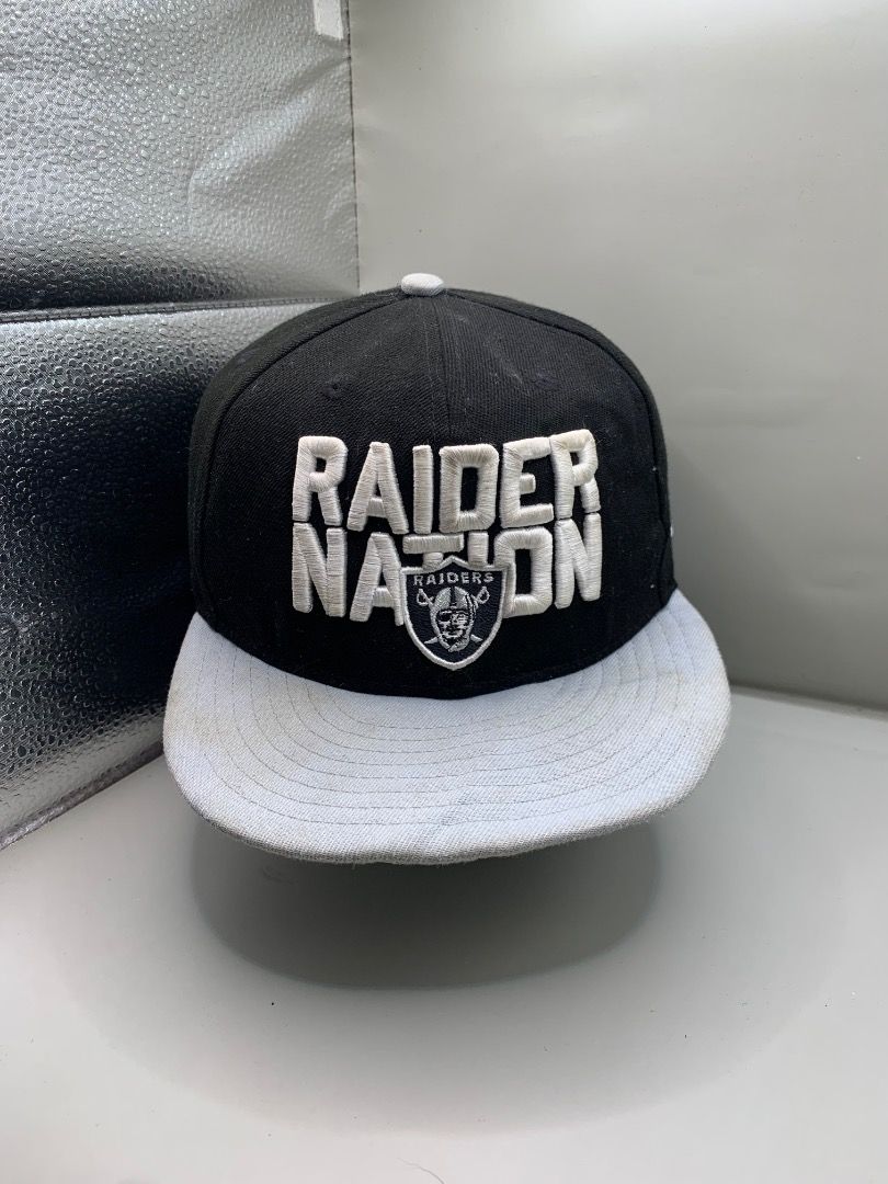 New Era NFL Raiders Nation Snapback Hat (Category: Caps & Hats) located in La Trinidad. Submitted by dfntlymon (Listing ID 1468600549, Image 2). Description: - Brand: New Era 9FIFTY - Team: Oakland Raiders - Color: Black crown with grey flat brim - Design: Bold 'RAIDER NATION' embroidery and team shield on front - Back: NFL logo patch and adjustable plastic snap strap (fits sizes 7 1/8 to 7 5/8) - Interior: Features iconic 'JUST WIN BABY' taping 