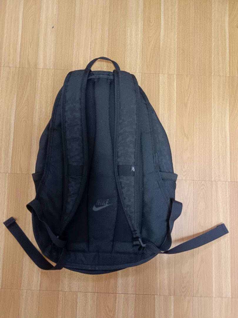 Nike Black Patterned Backpack (Category: Backpacks) located in Manila. Submitted by jaymarkmcacuyong (Listing ID 1468554425, Image 2). Description: - Brand: Nike - Color: Classic Black with subtle pattern texture - Storage: Multiple compartments with spacious interior - Pockets: Front vertical zip pocket and dual mesh side pockets for water bottles - Comfort: Adjustable padded shoulder straps with Nike branding patch - Versatility: Ideal for scho