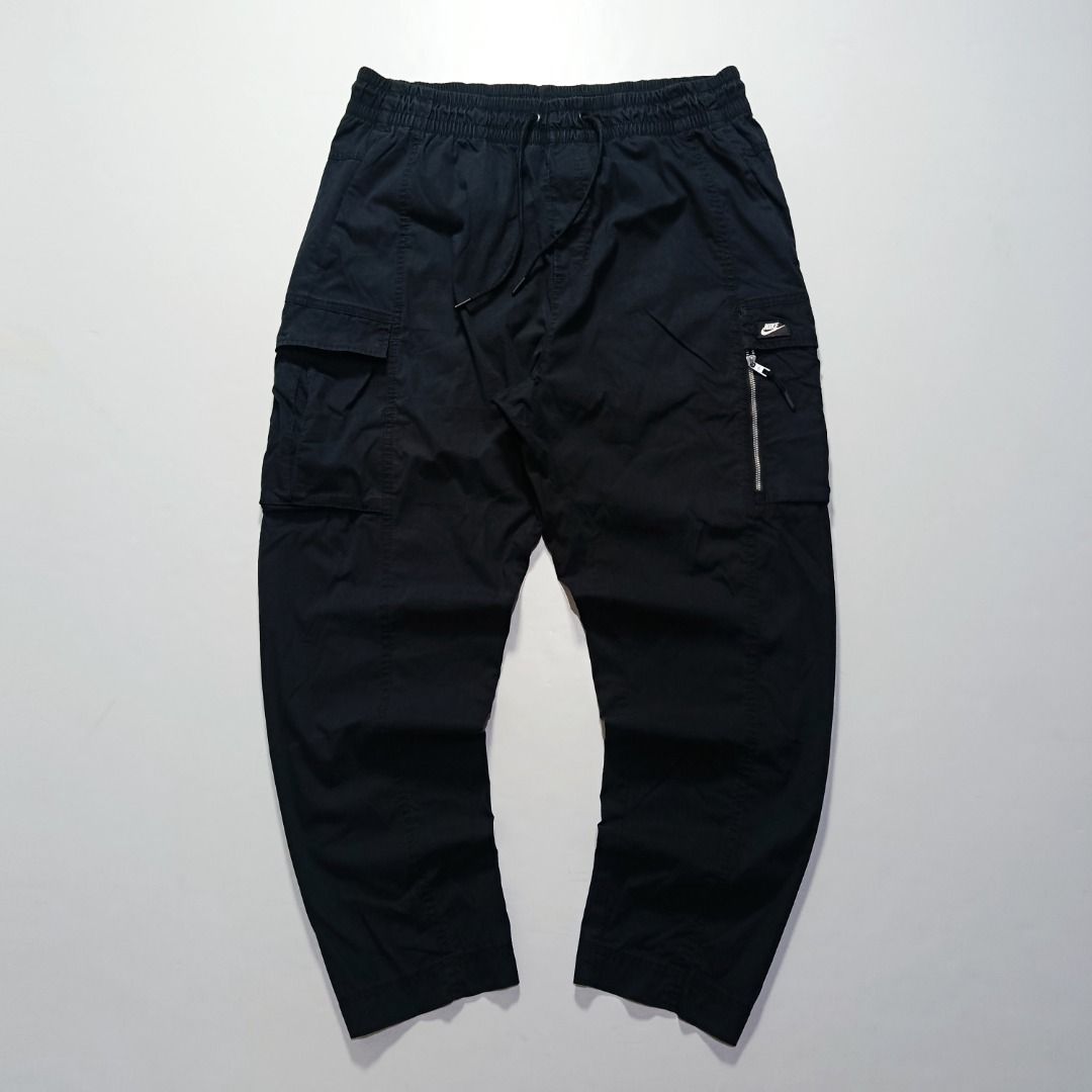 Nike Woven Cargo Pants with Zip Side Pocket (Category: Chinos) located in Taytay. Submitted by hoodgrail.vtg (Listing ID 1468623151, Image 1). Description: • Excellent condition - Like new • Black woven cargo pants featuring a zippered side pocket, utility cargo pockets, and Nike logo detailing • Size on tag: — best fits W32–34 (estimated; elastic waist) • Measurements: 16.5 x 39 in • Leg opening: 6.5 in • Color rate: 10/10 • Issue: Damaged edges