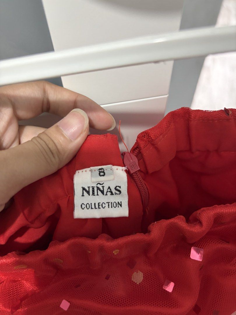 Ninas Collection Red Strapless Dress Size 8 (Category: Babies & Kids Fashion) located in Bulacan. Submitted by lenggayy (Listing ID 1468558905, Image 2). Description: - Brand: Nina's Collection - Color: Bright red - Size: 8 (tag attached near zipper) - Design: Strapless with gathered fabric across the bust - Details: Sparkly square sequins scattered over the mesh overlay fabric - Style: Bubble hem skirt - Closure: Back zipper.