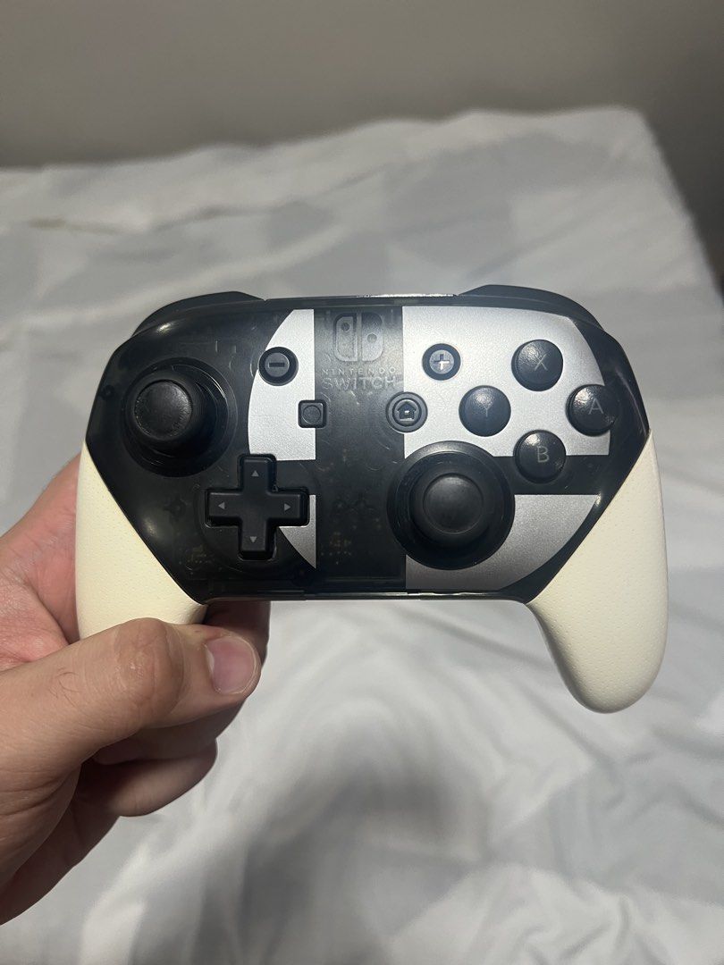 Nintendo Switch Pro Controller Super Smash Bros Edition (Category: Controllers) located in Cebu City. Submitted by swiftwater.9c307a (Listing ID 1468524392, Image 1). Description: - Official Super Smash Bros Ultimate Special Edition Pro Controller for Nintendo Switch - Stylish black translucent design with white grips and silver Smash logo - Fully wireless connectivity for comfortable gaming - Responsive dual thumbsticks, D-pad, and face buttons 