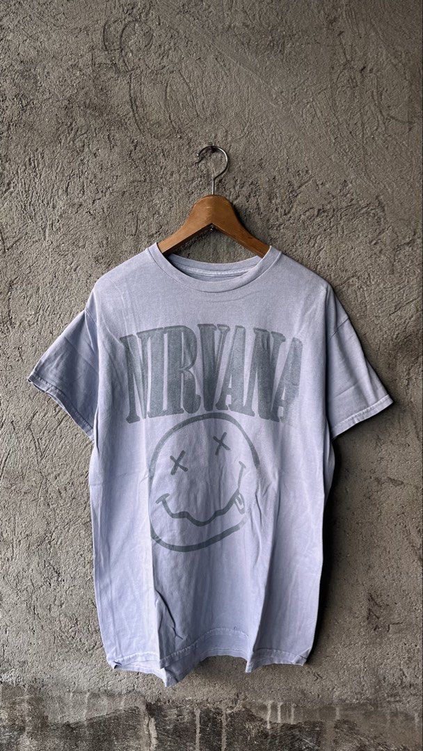 Nirvana Smiley Face Graphic Tee Acid Wash (Category: Tshirts & Polo Shirts ) located in Cabuyao City. Submitted by bulandos (Listing ID 1468636957, Image 1). Description: - Brand: Nirvana - Design: Classic smiley face print - Color/Style: Acid wash faded grey-blue - Size: Medium - Material: 100% cotton, tagless neck label - Condition: Pre-loved with one tiny hole near the bottom hem (shown in close-up photo).