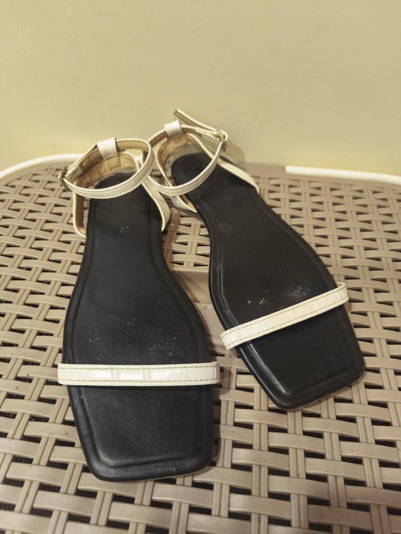 Olivia White and black flat sandals with ankle strap (Category: Flats & Sandals) located in Baguio. Submitted by zia_zab (Listing ID 1468530700, Image 1). Description: - Color: Classic black with a contrast white front strap - Design: Trendy square toe with secure ankle strap and buckle closure - Style: Simple, versatile flat sandals perfect for everyday casual outfits - Condition: Pre-loved with visible signs of wear and dirt on the soles - Budg