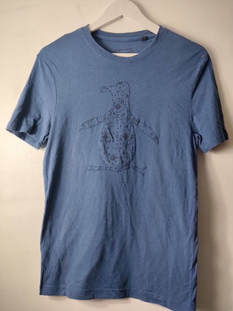 Original Penguin Blue Graphic Tee (Category: Tshirts & Polo Shirts ) located in Quezon City. Submitted by needforthrift (Listing ID 1468636273, Image 1). Description: - Brand: Original Penguin by Munsingwear - Size: Small (S) - Color: Blue - dimension: 18 width 27.5 length - Material: 100% cotton (super soft) - Fit: Standard fit with short sleeves - Design: Large penguin graphic on chest - Care: Machine washable - Origin: Made in El Salvador.