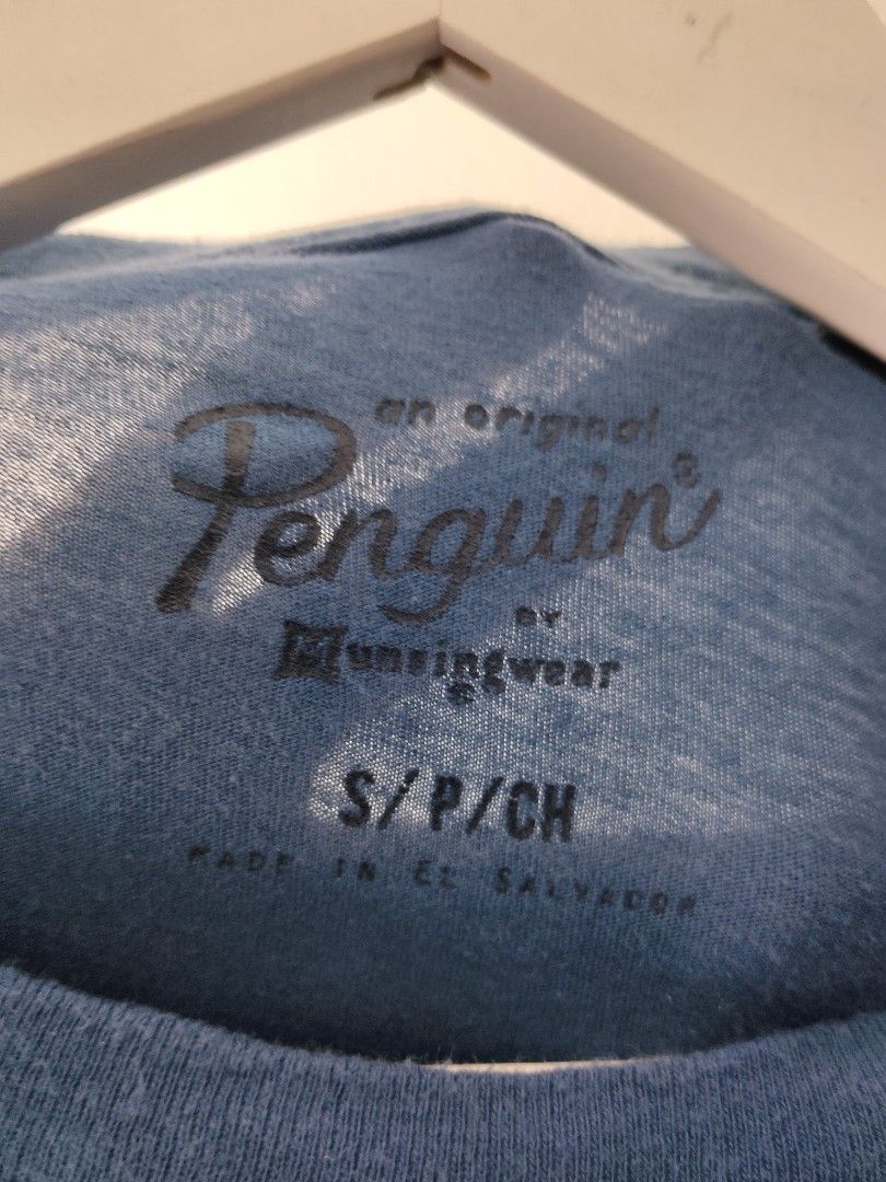 Original Penguin Blue Graphic Tee (Category: Tshirts & Polo Shirts ) located in Quezon City. Submitted by needforthrift (Listing ID 1468636273, Image 2). Description: - Brand: Original Penguin by Munsingwear - Size: Small (S) - Color: Blue - dimension: 18 width 27.5 length - Material: 100% cotton (super soft) - Fit: Standard fit with short sleeves - Design: Large penguin graphic on chest - Care: Machine washable - Origin: Made in El Salvador.