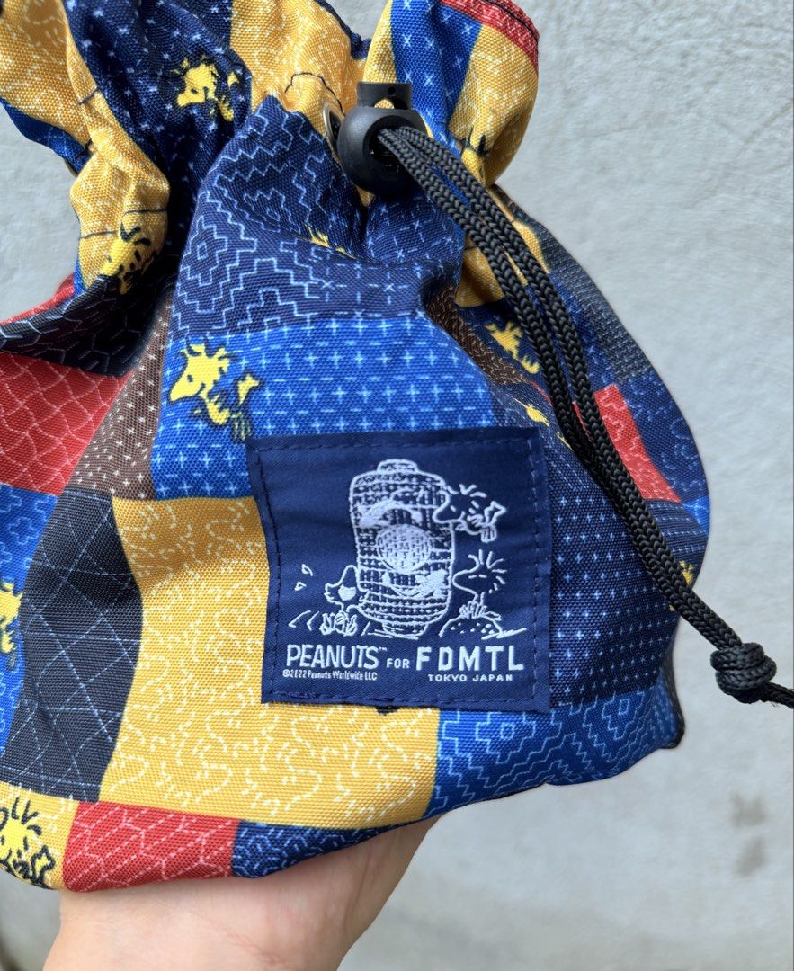 PEANUTS for FDMTL Tokyo Japan Patchwork Drawstring Bag (Category: Shoulder Bags) located in Baguio. Submitted by aalkharys (Listing ID 1468676163, Image 3). Description: - Authentic PEANUTS x FDMTL Tokyo collaboration - Eye-catching blue, yellow, and red patchwork design - Features iconic Snoopy and Woodstock graphics - Secure drawstring closure with an adjustable toggle - Dark blue shoulder strap and matching interior lining - Branded woven patc