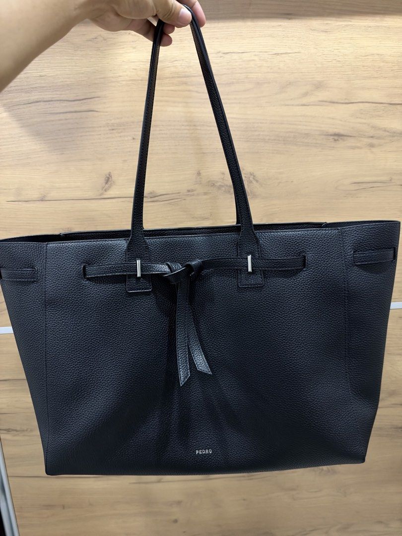 Pedro Black Demi Oversized (Category: Tote Bags) located in Pasig City. Submitted by hshmt (Listing ID 1468601924, Image 1). Description: Black pebble leather tote bag from Pedro. Structured shape with twin shoulder straps. Decorative front belt detail with knot and silver hardware. Spacious main interior compartment with embossed logo branding on the base. Clean textured finish all over. Bought last September @BGC.