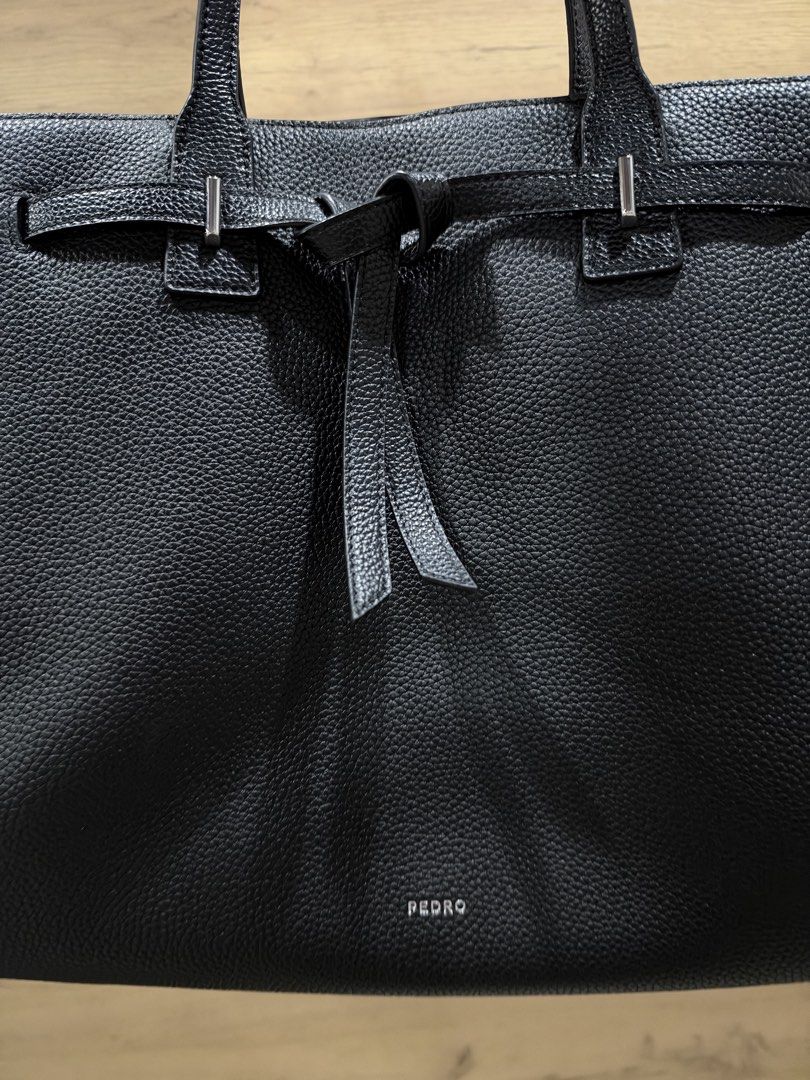 Pedro Black Demi Oversized (Category: Tote Bags) located in Pasig City. Submitted by hshmt (Listing ID 1468601924, Image 2). Description: Black pebble leather tote bag from Pedro. Structured shape with twin shoulder straps. Decorative front belt detail with knot and silver hardware. Spacious main interior compartment with embossed logo branding on the base. Clean textured finish all over. Bought last September @BGC.