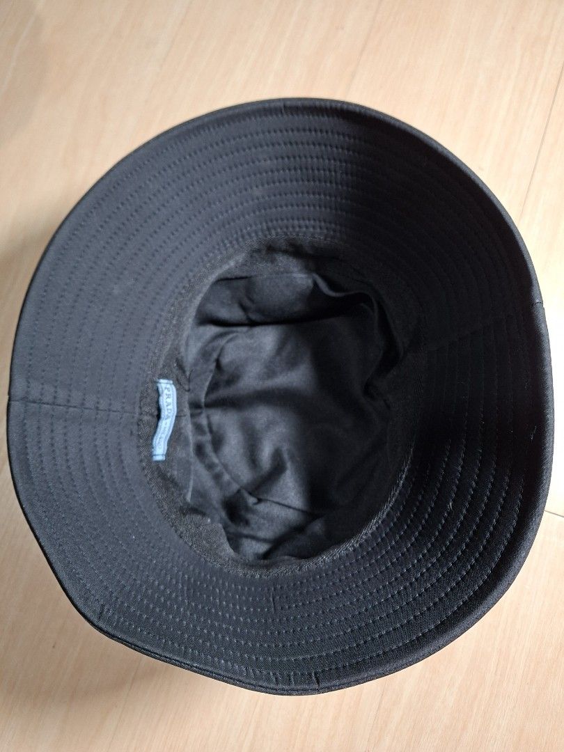 Prada Black Nylon Bucket Hat (Category: Caps & Hats) located in Baguio. Submitted by restyrille77846 (Listing ID 1468643779, Image 3). Description: - Color: Black - Material: Durable nylon - Details: Classic triangular metal logo plaque on the side, quilted stitching on the brim, and blue interior brand label - Condition: Clean surface with minimal signs of handling - Style: Great staple accessory for everyday outfits.
