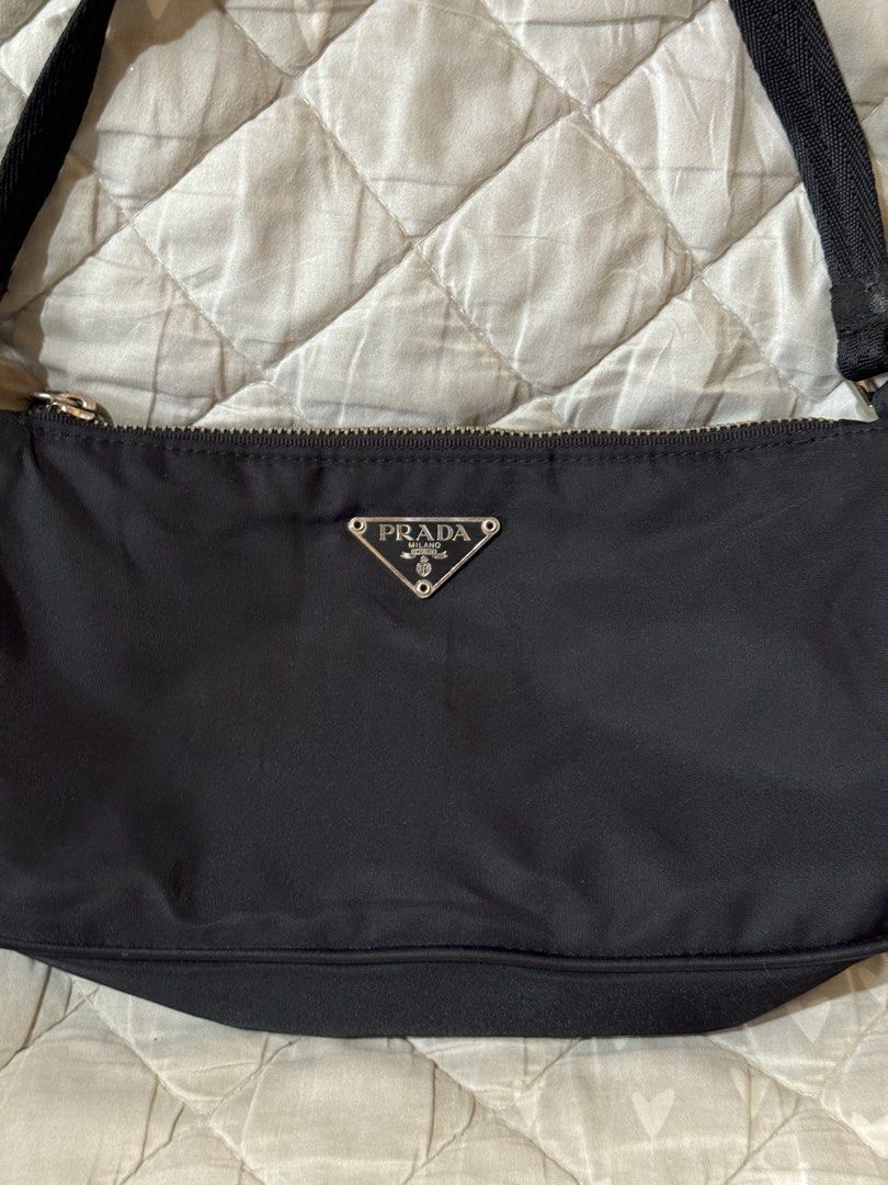 Prada Black Nylon pochette small (Category: Luxury Bags & Wallets) located in Danao, Cebu. Submitted by jojie.1983 (Listing ID 1468578730, Image 2). Description: - Brand: Prada thrift source expect normal sign of use - Small size - Style: Nylon Material pochette - not lampo zipper no white tag - Color: Classic Black with Silver-Tone Hardware - Features: Iconic metal triangle logo, zip top closure, and comfortable shoulder strap with metal buckles