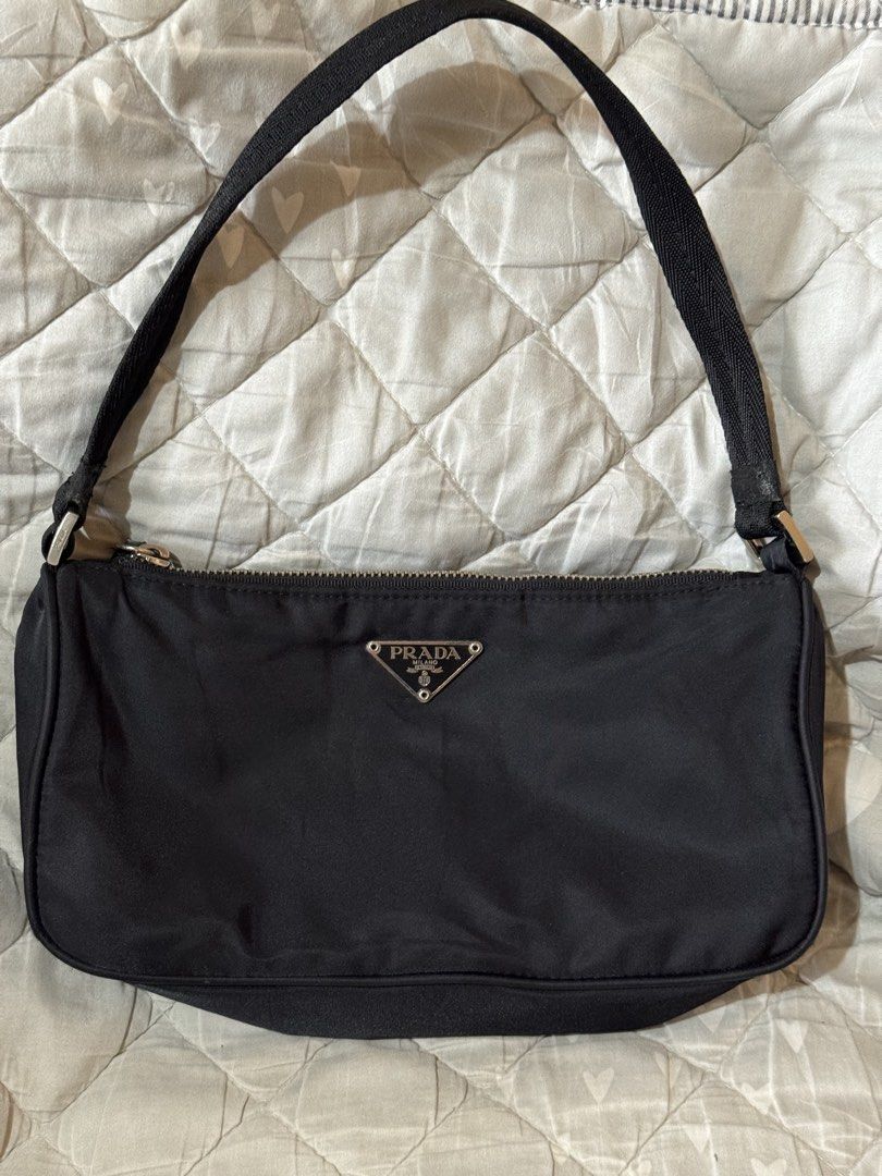Prada Black Nylon pochette small (Category: Luxury Bags & Wallets) located in Danao, Cebu. Submitted by jojie.1983 (Listing ID 1468578730, Image 1). Description: - Brand: Prada thrift source expect normal sign of use - Small size - Style: Nylon Material pochette - not lampo zipper no white tag - Color: Classic Black with Silver-Tone Hardware - Features: Iconic metal triangle logo, zip top closure, and comfortable shoulder strap with metal buckles