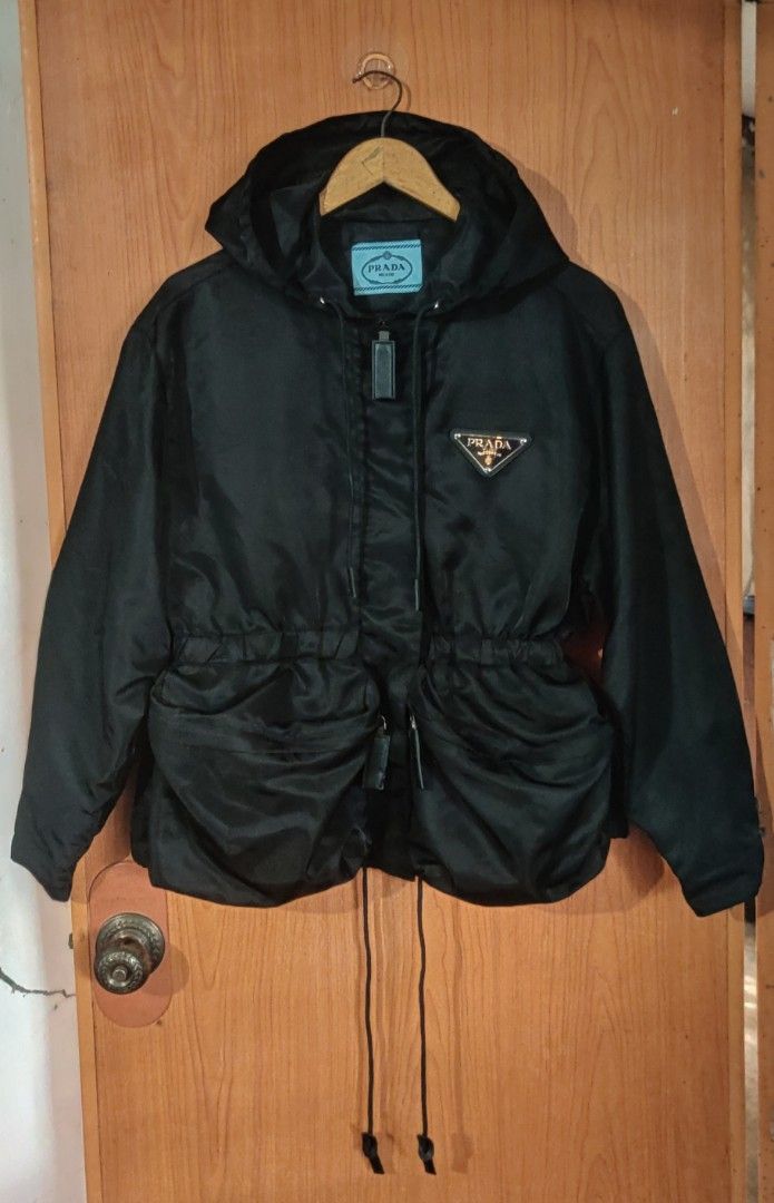 Prada Re Nylon Gabardine Jacket (Category: Coats, Jackets and Outerwear) located in Bago City. Submitted by louielinco (Listing ID 1468628040, Image 1). Description: - Brand: Prada - Item: Hooded Nylon Jacket - Size: Small On Tag Best Fit To Large Women's - Color: Classic Black - Details: Iconic triangular logo plaque on chest, dual front utility pockets, and adjustable waist drawstrings - Closure: Full front zip with snap buttons stamped with Pr