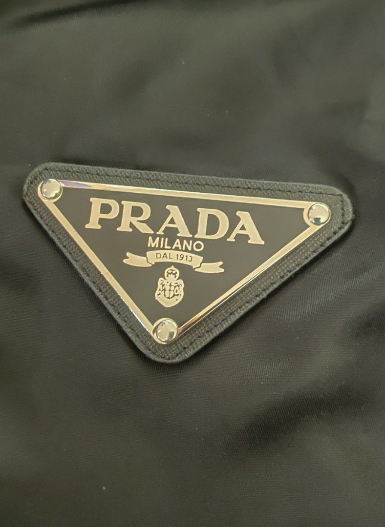 Prada Re Nylon Gabardine Jacket (Category: Coats, Jackets and Outerwear) located in Bago City. Submitted by louielinco (Listing ID 1468628040, Image 3). Description: - Brand: Prada - Item: Hooded Nylon Jacket - Size: Small On Tag Best Fit To Large Women's - Color: Classic Black - Details: Iconic triangular logo plaque on chest, dual front utility pockets, and adjustable waist drawstrings - Closure: Full front zip with snap buttons stamped with Pr