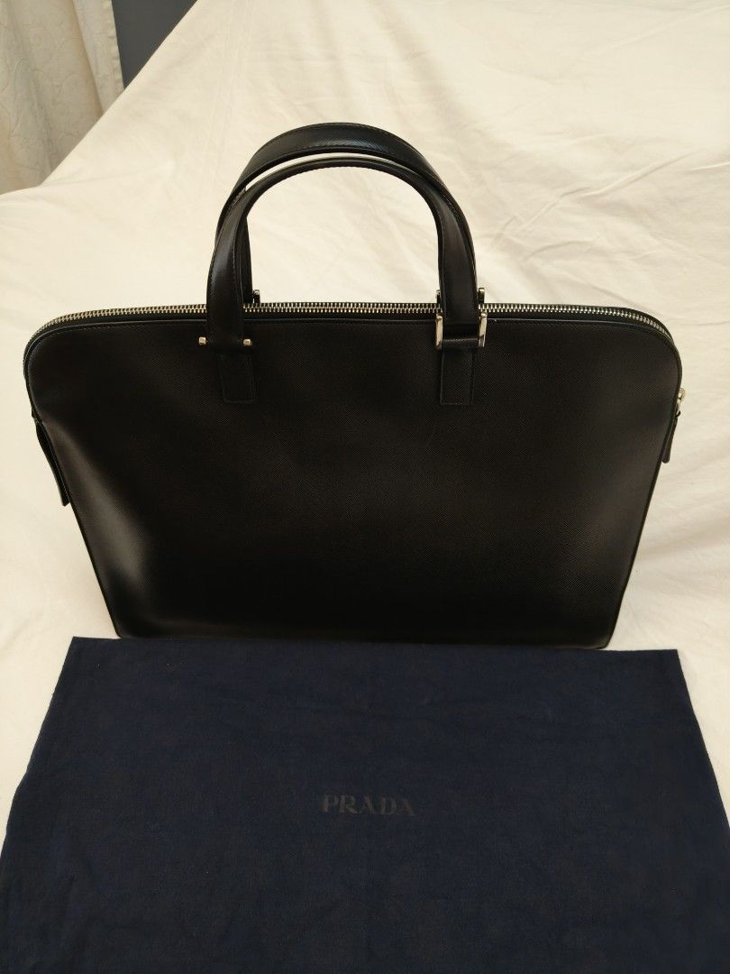 Prada Saffiano Leather Triangle Briefcase (Category: Luxury Bags & Wallets) located in Makati City. Submitted by emem.pre.owned.ph (Listing ID 1468547485, Image 2). Description: Brand: Prada -Model: Saffiano Leather Triangle Briefcase -Material: Saffiano leather -Hardware: Silver-coloured -Dimensions: 29 x 40 x 9.5 cm -Interior: Very good -Accessories: Authenticity card, dustbag -Carry style: Handbag.