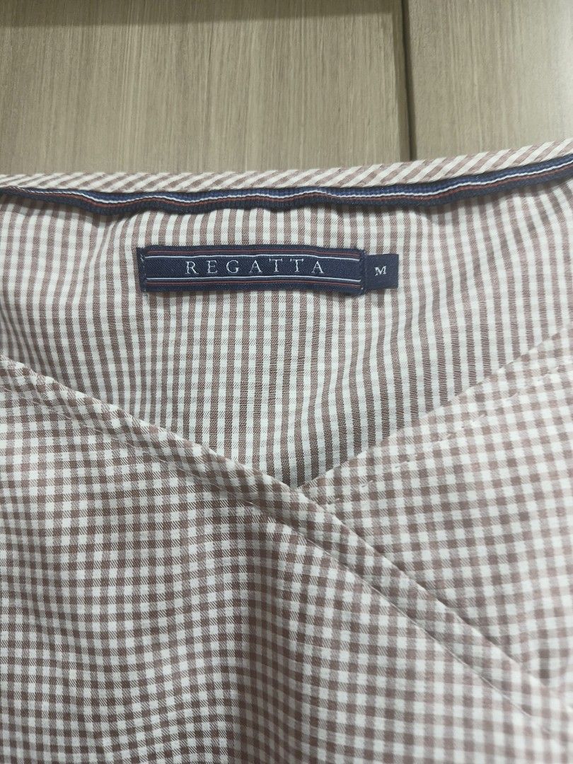 Regatta blouse (Category: Blouses) located in Quezon City. Submitted by majasaw88 (Listing ID 1468573014, Image 2). Description: - Brand: Regatta - Size: Medium - Design: Brown and white checkered print, square neckline, wrap-style front - Sleeves: Short puff sleeves with elastic cuffs - Fabric: Lightweight, ideal for warm weather and casual wear.