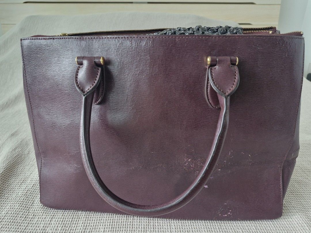 RLL Burgundy Leather Tote Bag (Category: Tote Bags) located in Quezon City. Submitted by acey18 (Listing ID 1468569299, Image 2). Description: - Brand: LRalph Lauren (RLL) - Style: Structured tote bag in a rich dark burgundy leather - Hardware: Elegant gold-tone accents with front embossed RLL monogram - Interior: Multiple zip compartments and handy slip pockets - Closure: Rolled top handles and magnetic snap gussets - strap included - Condition: