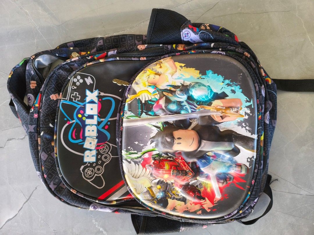 Roblox Gamer Backpack School Bag Multi Compartment (Category: Babies & Kids Fashion) located in Munoz. Submitted by toy_zone (Listing ID 1468501492, Image 1). Description: - Design: Cool Roblox graphic print with game controllers and block characters on a black background - Comfort: Padded back support and adjustable shoulder straps with durable plastic buckles - Storage: Multiple zipper pockets to keep your daily essentials organized - Condition