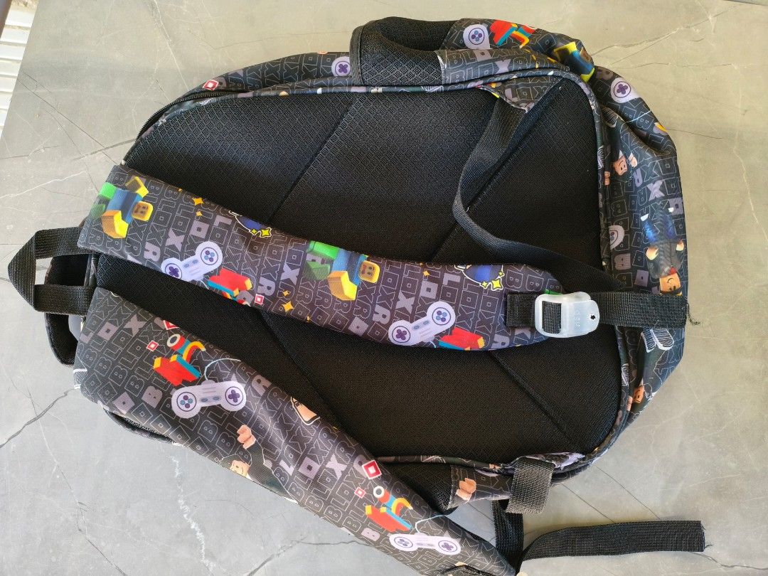 Roblox Gamer Backpack School Bag Multi Compartment (Category: Babies & Kids Fashion) located in Munoz. Submitted by toy_zone (Listing ID 1468501492, Image 2). Description: - Design: Cool Roblox graphic print with game controllers and block characters on a black background - Comfort: Padded back support and adjustable shoulder straps with durable plastic buckles - Storage: Multiple zipper pockets to keep your daily essentials organized - Condition