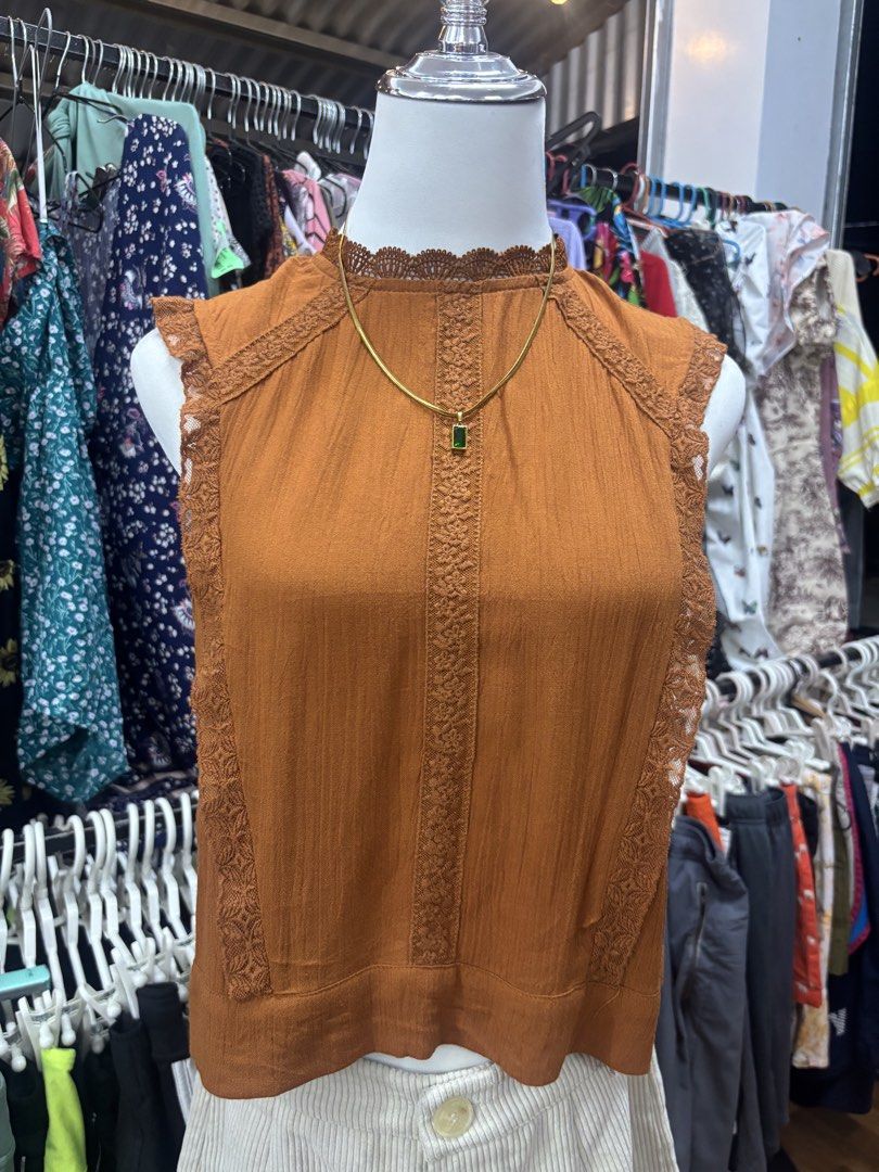 Rust Brown Lace Trim Sleeveless Tie-Back Top (Category: Sleeveless) located in Alicia. Submitted by thriftbagph (Listing ID 1468636017, Image 1). Description: -Small to semi med size - Color: Rust brown - Style: Sleeveless top with mock neck - Details: Delicate lace trim on collar and arm openings, vertical crochet lace panels on front - Back Design: Keyhole opening with top button and self-tie bow at the hem - Fabric: Lightweight and textured - 