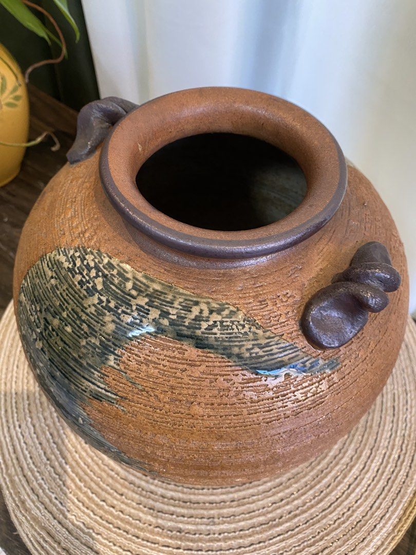 Rustic textured ceramic pottery vase with handles (Category: Vases & Decorative Bowls) located in San Pedro. Submitted by jingay81 (Listing ID 1468708681, Image 3). Description: - Round textured ceramic vase in earthy brown tones - Features a striking dark brushed glaze accent on the front - Elegant ribbed finish throughout the body - Small sculpted handles on opposite sides of the rim - Wide circular top opening and solid base - Unique handcraft
