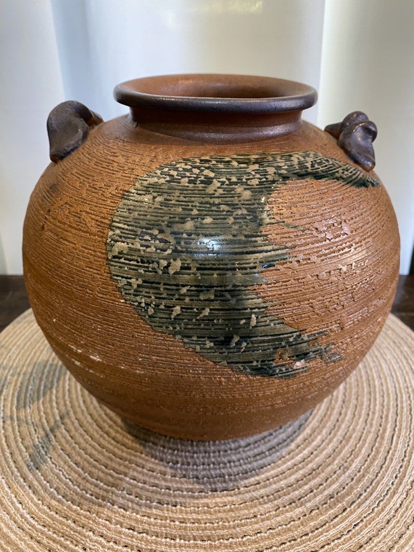 Rustic textured ceramic pottery vase with handles (Category: Vases & Decorative Bowls) located in San Pedro. Submitted by jingay81 (Listing ID 1468708681, Image 1). Description: - Round textured ceramic vase in earthy brown tones - Features a striking dark brushed glaze accent on the front - Elegant ribbed finish throughout the body - Small sculpted handles on opposite sides of the rim - Wide circular top opening and solid base - Unique handcraft