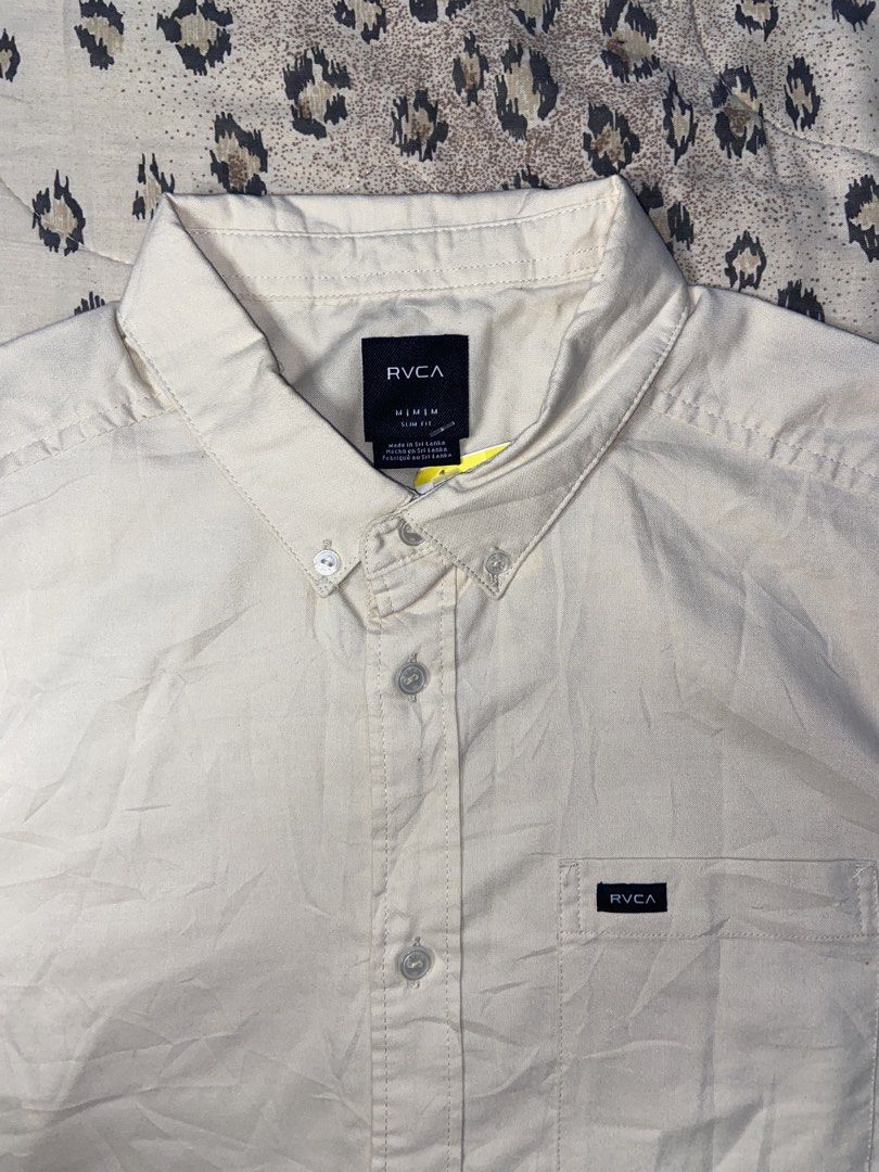 RVCA Short Sleeve Button Down Shirt Slim Fit Medium (Category: Tshirts & Polo Shirts ) located in Manila. Submitted by nix.thrift (Listing ID 1468608246, Image 2). Description: - Brand: RVCA - Style: Short sleeve button-down shirt with button-down collar - Color: Cream - Size: Men's Medium (Slim Fit) - Details: Single chest pocket with woven brand label - Condition: Brand new with original tags attached, unworn.