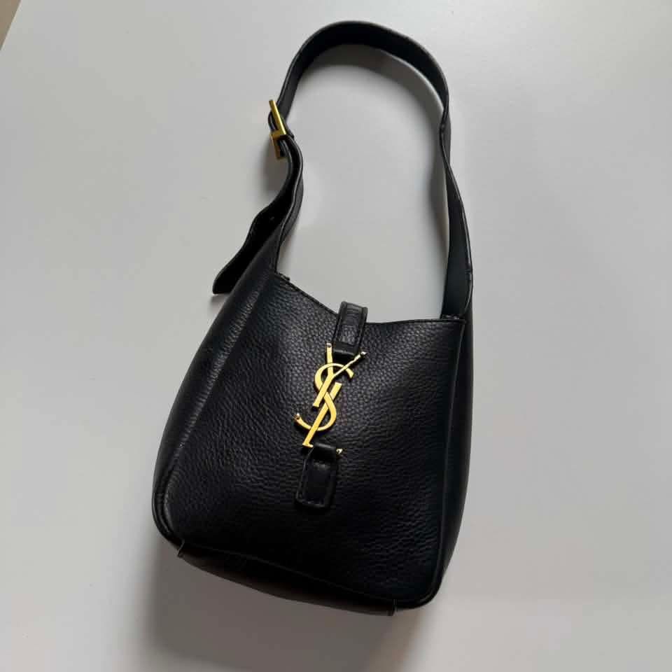 Saint Laurent (YSL) (Category: Luxury Bags & Wallets) located in Bacolod. Submitted by lux.antithrifts (Listing ID 1468628221, Image 3). Description: Brand: Saint Laurent (YSL) Model: Le 5 à 7 Supple Small Hobo Bag Color: Black Material: Grained Calfskin Leather with a soft, supple texture and tonal suede lining. Hardware: Light bronze / gold-tone metal hardware featuring the iconic Cassandre (YSL) logo leather tab closure..