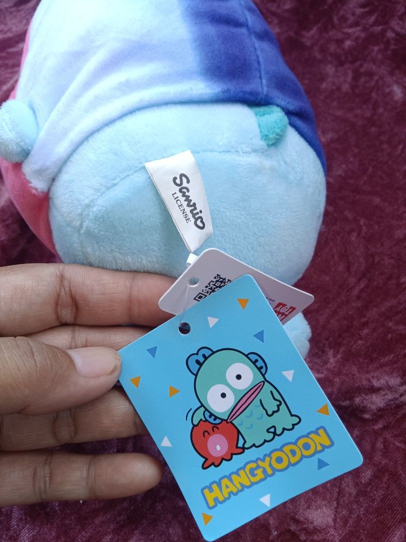 Sanrio Hangyodon Plush Toy with Tag (Category: Plushies & Soft Toys) located in Cabuyao City. Submitted by jimcollections (Listing ID 1468685247, Image 2). Description: - 100% Authentic Sanrio official merchandise - Features Hangyodon in a cute pink and white hood - Includes original Hangyodon tag and Sanrio back license tag - Super soft blue plush body with big expressive eyes and sweet little feet - Equipped with a top hanging loop for easy dis
