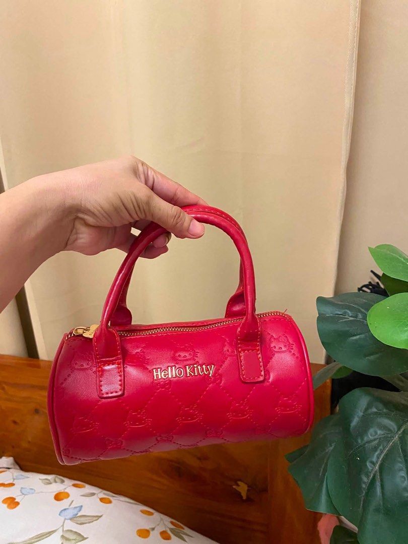 Sanrio Hello Kitty Red Quilted Cylinder Handbag (Category: Purses & Pouches) located in Manila. Submitted by janetecson05 (Listing ID 1468645731, Image 1). Description: Hk MINISO BAG Red Sanrio Kitty barrel handbag. Quilted pattern with embossed Kitty faces across the faux leather exterior. Gold hardware, including a cute bow-shaped zipper pull. Matching red fabric lining inside decorated with little Kitty outlines and bows. Dual top handles and 