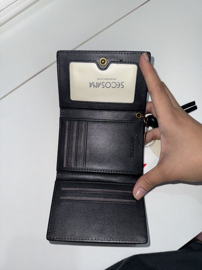 Secosana Black Tri-fold Wallet (Category: Wallets & Card holders) located in Manila. Submitted by chi.declutter (Listing ID 1468524079, Image 2). Description: - Brand new with tag attached - Sleek black tri-fold design made from smooth faux leather - Multiple card slots and a convenient ID window - Chic gold hardware accent and black zipper pull - Clean stitching and compact size, ideal for everyday use Free delivery for those who will avail 5 it