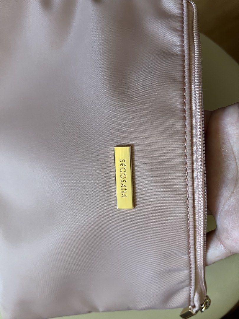 Secosana Pink Wristlet Clutch Pouch (Category: Clutches) located in Rizal. Submitted by s0apandglory (Listing ID 1468557627, Image 3). Description: - Brand: Secosana - Material: Durable nylon in a chic dusty pink shade - Hardware: Elegant gold-toned hardware with front metal logo - Strap: Includes a matching detachable wrist strap - Closure: Top zip with a branded pull tab - Interior: Clean grey lining with one main compartment, slip pockets, and