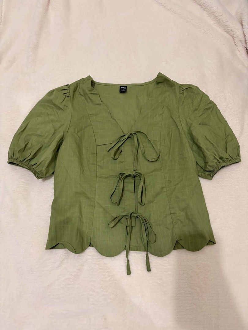 SHEIN Green Tie Front Scallop Hem Blouse (Category: Blouses) located in Manila. Submitted by janellecas75114 (Listing ID 1468644784, Image 1). Description: - Brand: SHEIN - Color: Green - Size: S (Fits EU 36 / US 4) - Style: V-neck with 3 front tie closures, puff sleeves with elastic cuffs, and scalloped hem - Fabric: Lightweight textured material with a subtle grid pattern - Condition: Great, clean, and ready to wear.
