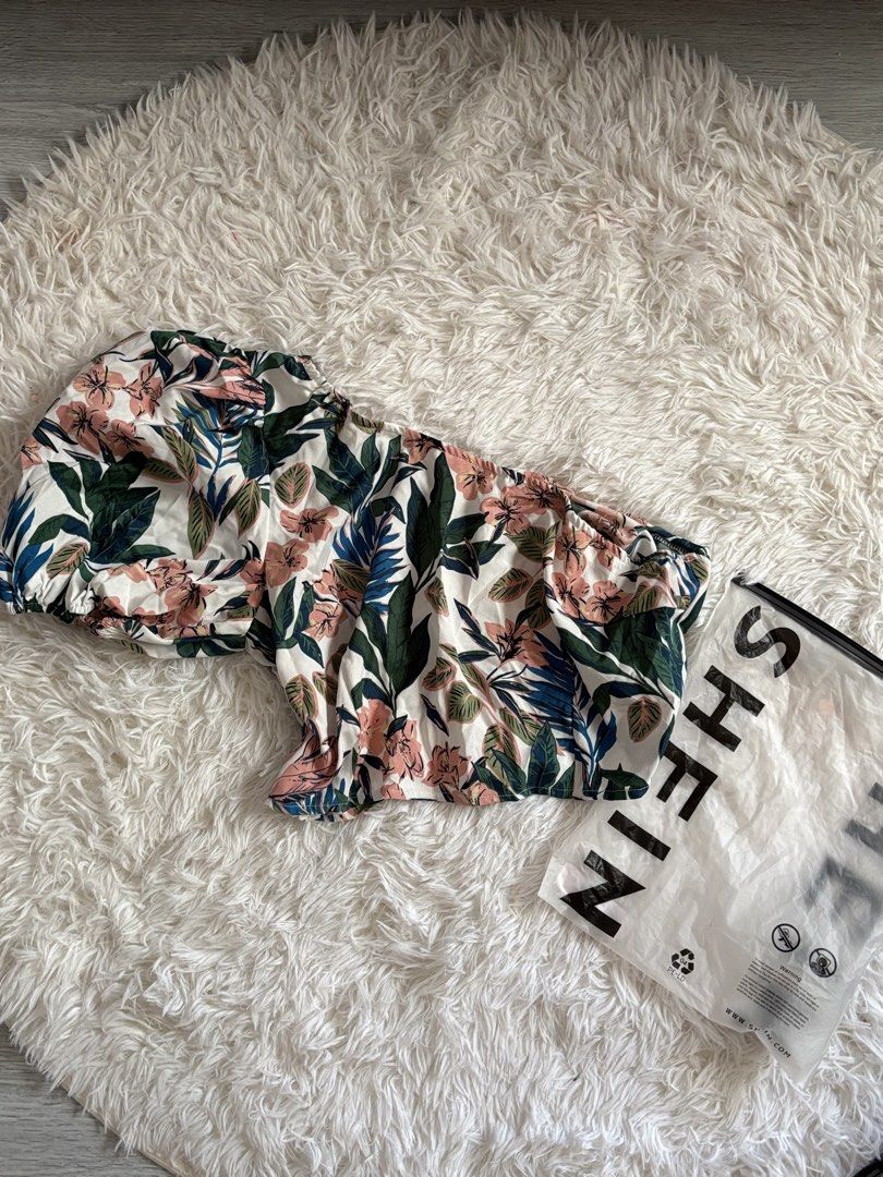 SHEIN Off-Shoulder Floral Crop Top (Category: Sleeveless) located in Quezon City. Submitted by lovedbysloane (Listing ID 1468598050, Image 1). Description: - Brand: SHEIN - Style: Off-shoulder crop top with elasticated neckline and cuffs - Design: Tropical pink and green floral/leaf pattern on white - Material: Lightweight and breathable, ideal for warm weather - Condition: Brand new in original plastic packaging.