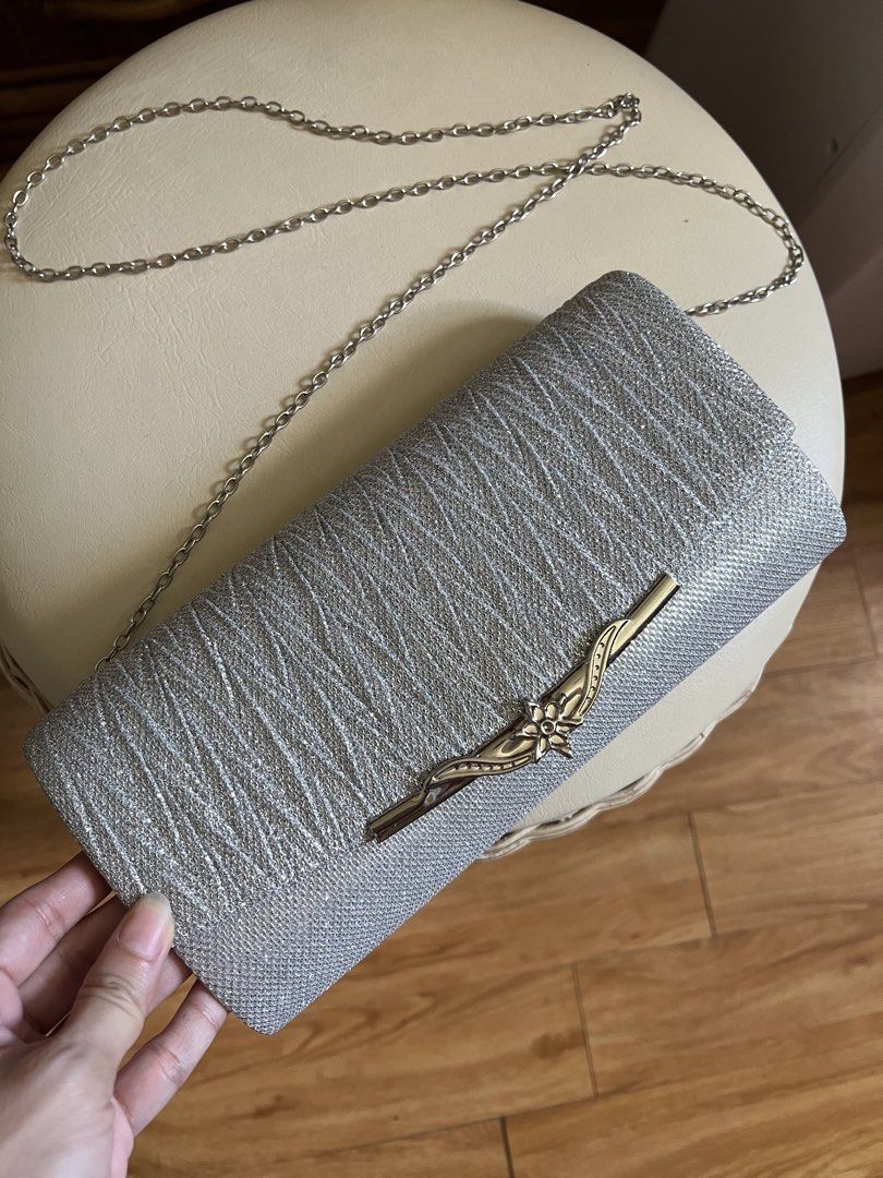 Silver Glitter Evening Clutch Bag with Chain (Category: Clutches) located in Rizal. Submitted by s0apandglory (Listing ID 1468554642, Image 1). Description: - Color/Material: Silver glitter with textured fabric - Hardware: Sleek metallic detail on front flap - Closure: Secure magnetic snap - Interior: Clean white lined compartment - Strap: Includes detachable silver chain for shoulder wear - Occasion: Compact and chic for parties, weddings, and f