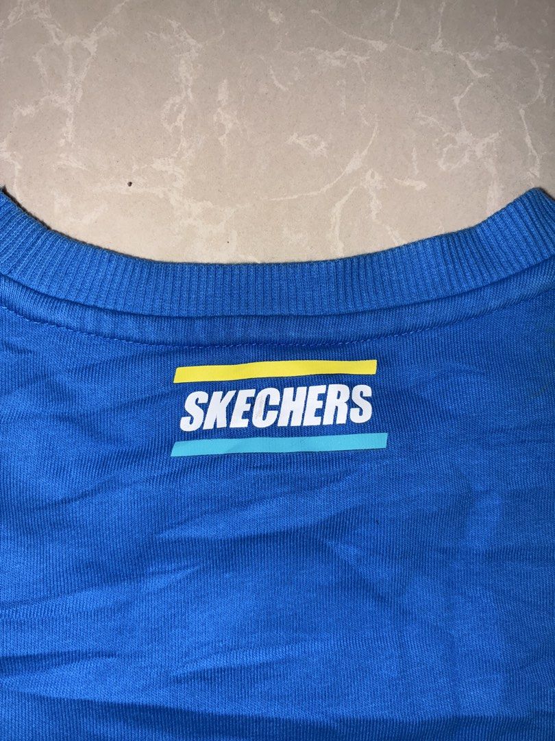 Skechers Blue Sweatshirt with Logo (Category: Coats, Jackets and Outerwear) located in Placer. Submitted by talaalond61563 (Listing ID 1468710204, Image 3). Description: - Brand: Skechers - Color: Bright blue with white, yellow, and teal accents - Style: Casual long-sleeve pullover crewneck sweatshirt - Details: Large 'S' logo graphic with accent stripes on front, matching branding near back neckline, and branded inside collar taping - Fit: Ribbe