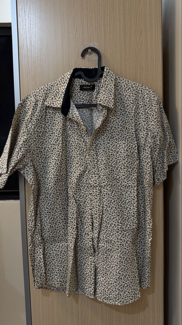 Smart Short Sleeve Floral Button Up Shirt (Category: Tshirts & Polo Shirts ) located in Quezon City. Submitted by declutterw_v (Listing ID 1468682133, Image 1). Description: - Brand: Smart - Style: Short sleeve button-up shirt - Color/Design: Cream base with an all-over small black floral vine print - Details: Contrast black inner collar and standard front button closure - Fabric: Lightweight, ideal for warm weather and casual outings - Fit: Stan