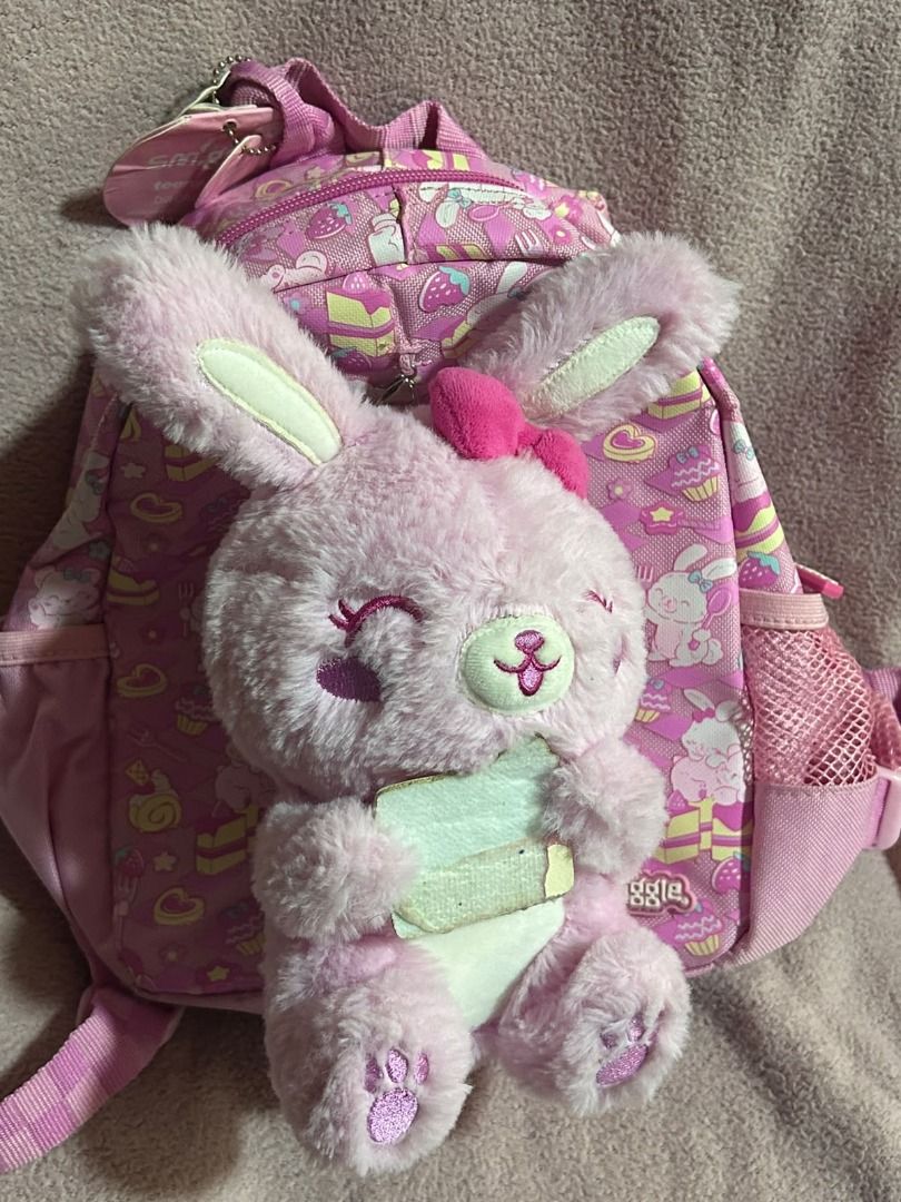 Smiggle Backpack with Removable Plush Toy Pink (Category: Backpacks) located in Las Pinas. Submitted by whatzupriley (Listing ID 1468549755, Image 1). Description: - Brand: Smiggle Teeny Tiny - Design: Bright pink with all-over dessert and bunny pattern - Bonus: Includes a detachable fluffy pink bunny plush toy - Features: Pink mesh side pockets and adjustable straps - see photos for details - Ideal for: Kids.
