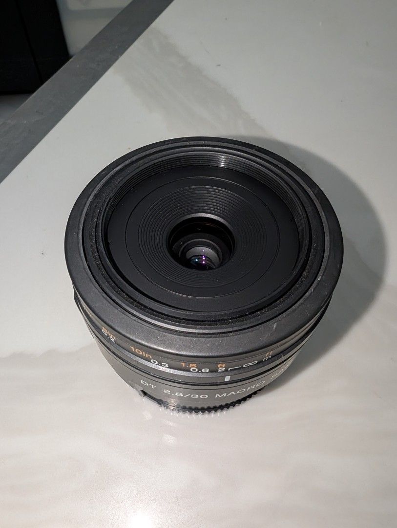Sony DT 2.8/30 Macro SAM Lens (Category: Lens & Kits) located in Santa Rosa. Submitted by vansting (Listing ID 1468505211, Image 2). Description: - Model: Sony DT 2.8/30 Macro SAM lens - Mount: Sony Alpha mount - Type: Compact prime lens ideal for macro and close-up photography - Features: Focus distance scale in feet and meters, standard AF/MF switch - Condition: Clean glass elements inside - Inclusion: Front lens cap with iconic orange Alpha lo