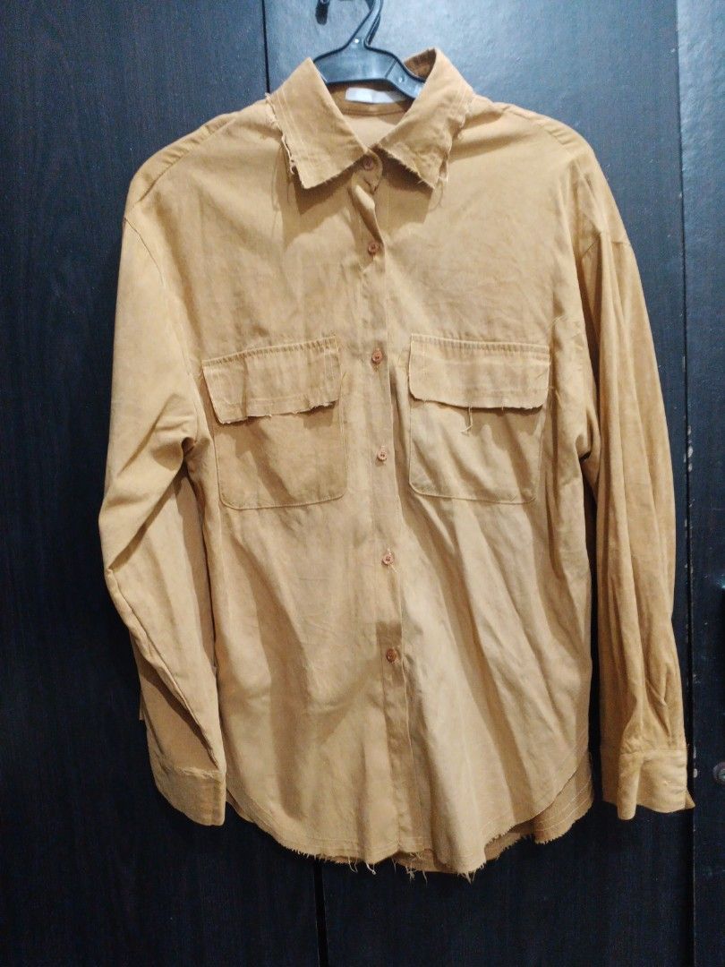 Tan Button-Up Shirt with Distressed Edges (Category: Shirts) located in Manila. Submitted by ggarage.sale (Listing ID 1468689931, Image 3). Description: - Color: Tan - Material: Soft suede-like fabric - Fit: Relaxed, oversized with drop shoulders - Details: Two front chest pockets with button flaps, brown front buttons - Style: Raw, distressed frayed edges on collar and hem for a vintage look - Usage: Versatile layering piece for casual outfits.