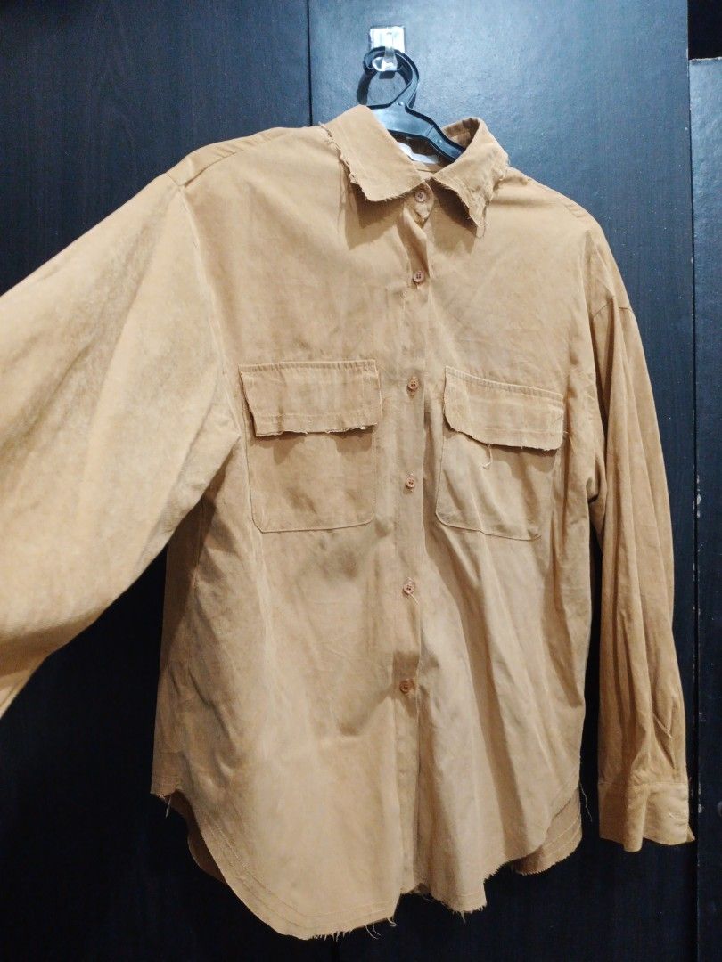 Tan Button-Up Shirt with Distressed Edges (Category: Shirts) located in Manila. Submitted by ggarage.sale (Listing ID 1468689931, Image 2). Description: - Color: Tan - Material: Soft suede-like fabric - Fit: Relaxed, oversized with drop shoulders - Details: Two front chest pockets with button flaps, brown front buttons - Style: Raw, distressed frayed edges on collar and hem for a vintage look - Usage: Versatile layering piece for casual outfits.