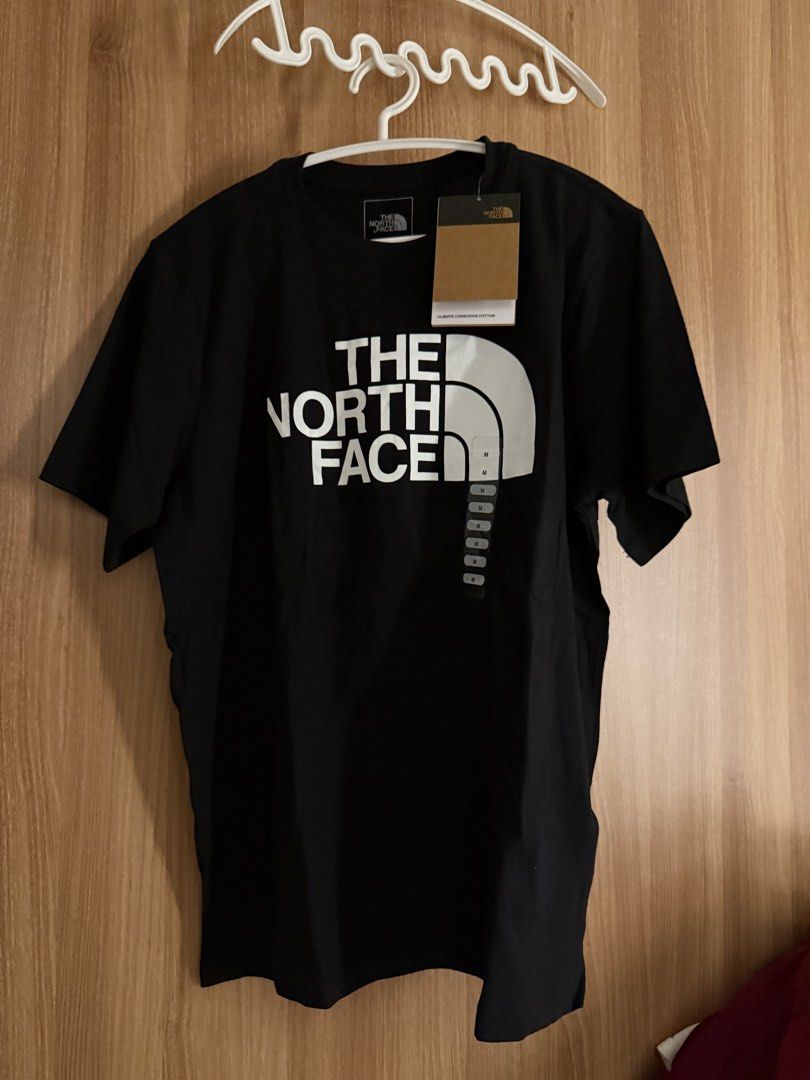 The North Face Black T-Shirt M (Category: Shirts) located in Manila. Submitted by conradfisher (Listing ID 1468631472, Image 1). Description: - Brand: The North Face - Color: Black with large white chest logo - Size: Medium (tag attached) - Fit: Regular fit with classic crew neck and short sleeves - Material: Climate-conscious cotton - Condition: Brand new with original tags.