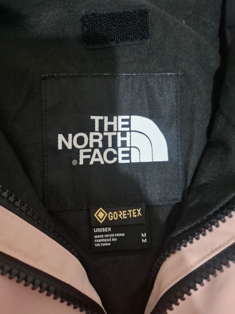 The North Face Gore-Tex Pink Black Jacket Size M (Category: Coats, Jackets and Outerwear) located in Manila. Submitted by necklie_tuballas (Listing ID 1468657184, Image 3). Description: - Brand: The North Face - Material: Gore-Tex waterproof shell - Colorway: Light pink and black - Size: Unisex Medium (M) - Origin: Made in Vietnam - Features: Attached hood with drawstrings, full zip front with snap-button storm flap - Details: All interior tags i