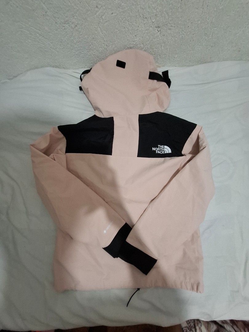 The North Face Gore-Tex Pink Black Jacket Size M (Category: Coats, Jackets and Outerwear) located in Manila. Submitted by necklie_tuballas (Listing ID 1468657184, Image 2). Description: - Brand: The North Face - Material: Gore-Tex waterproof shell - Colorway: Light pink and black - Size: Unisex Medium (M) - Origin: Made in Vietnam - Features: Attached hood with drawstrings, full zip front with snap-button storm flap - Details: All interior tags i